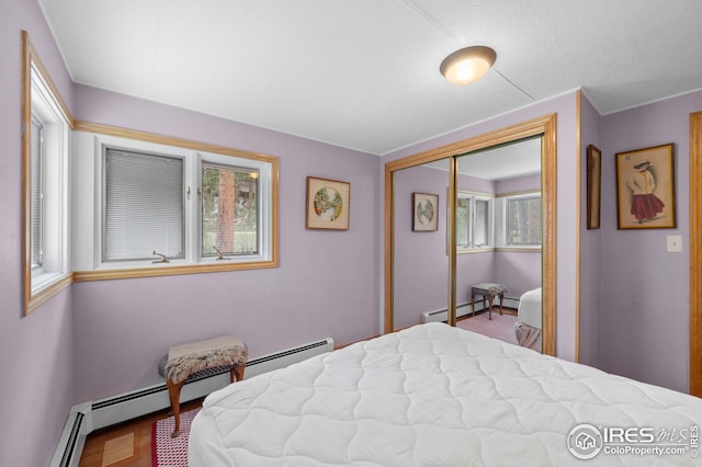 bedroom featuring multiple windows, a baseboard radiator, and a closet