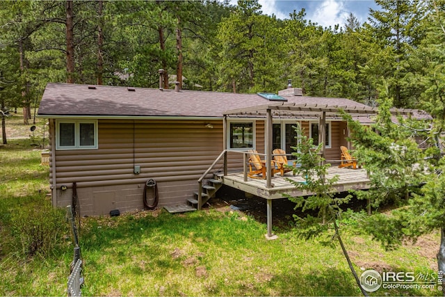 rear view of property featuring a wooden deck, a pergola, and a yard
