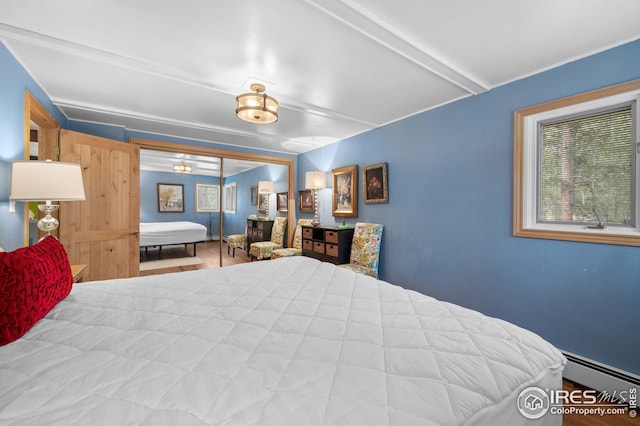 bedroom with beamed ceiling and a baseboard heating unit