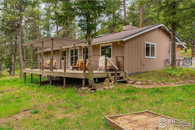 back of house with a wooden deck, a lawn, and a pergola