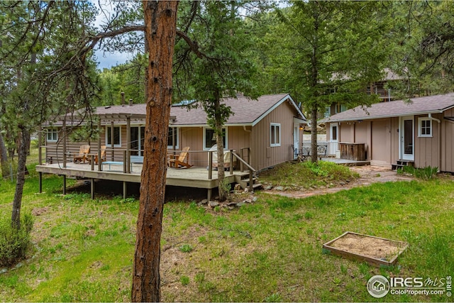 rear view of house featuring a wooden deck and a yard