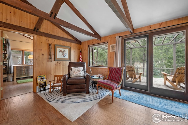 sitting room featuring wood-type flooring, lofted ceiling with beams, and wooden walls