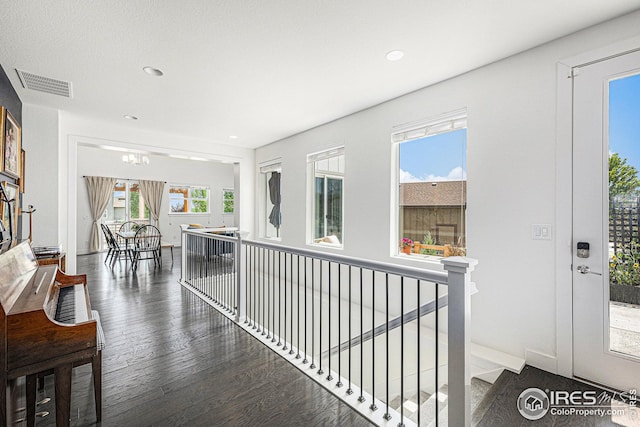 hall featuring dark hardwood / wood-style flooring, a wealth of natural light, and an inviting chandelier