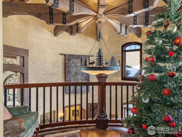 living room featuring wood-type flooring, a fireplace, beam ceiling, and a high ceiling