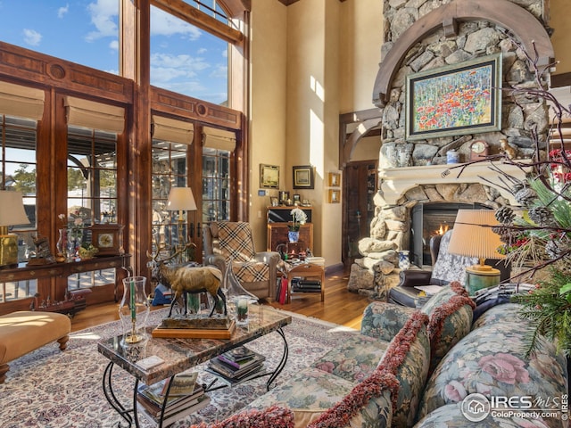 interior space with hardwood / wood-style floors, a stone fireplace, and a high ceiling