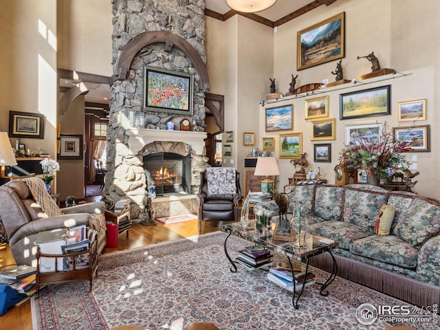 living room featuring hardwood / wood-style flooring, a towering ceiling, ornamental molding, and a fireplace