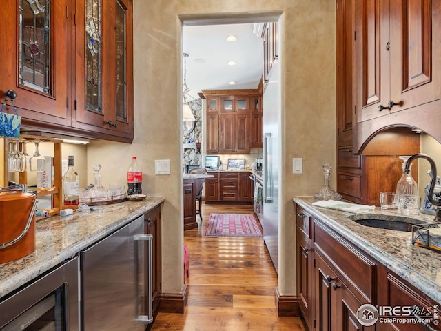 bar featuring wine cooler, sink, light stone counters, and light hardwood / wood-style floors