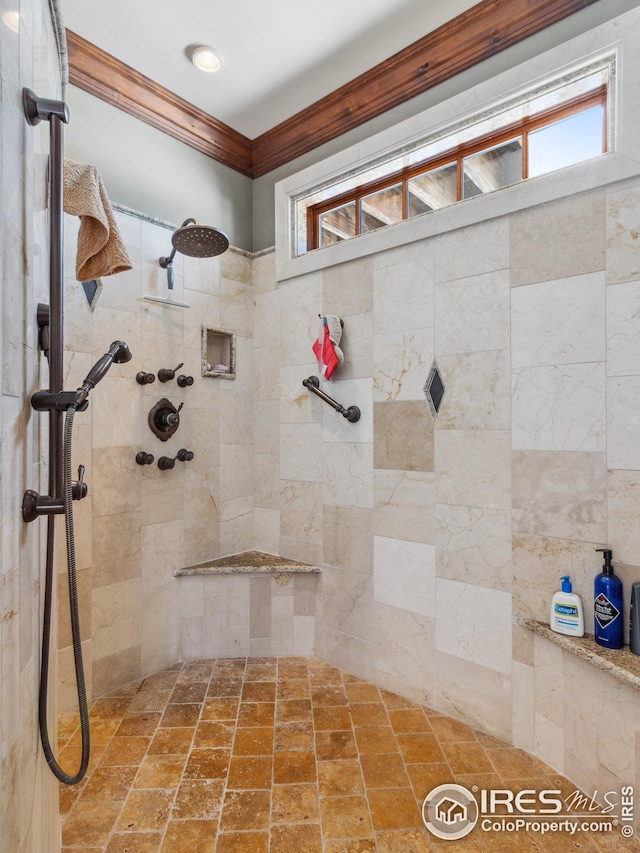 bathroom with a tile shower, a wealth of natural light, and ornamental molding