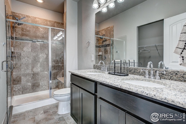 bathroom with a shower with door, vanity, and toilet