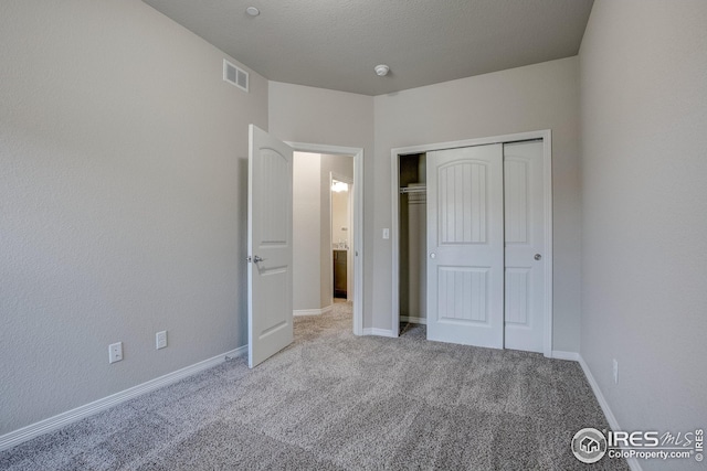 unfurnished bedroom with light carpet and a closet