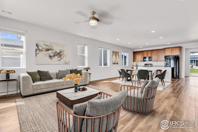 living area featuring light wood-style flooring, a ceiling fan, baseboards, recessed lighting, and visible vents