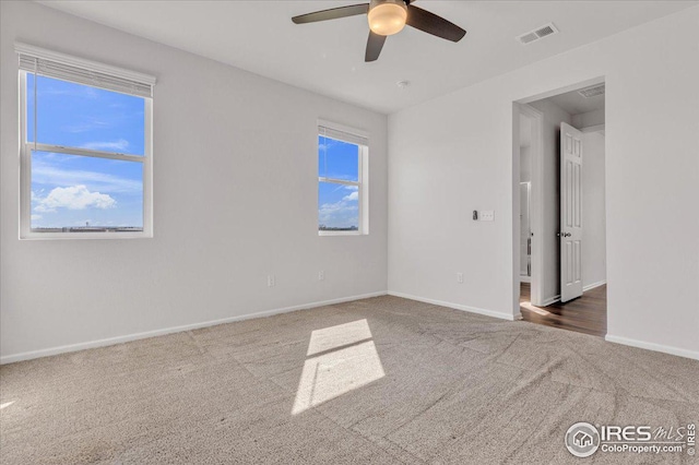carpeted spare room featuring visible vents, a ceiling fan, and baseboards