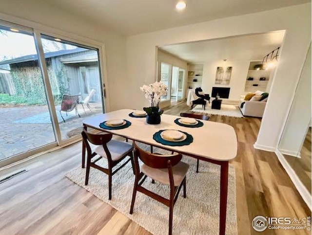 dining space featuring visible vents, wood finished floors, a fireplace, and a healthy amount of sunlight