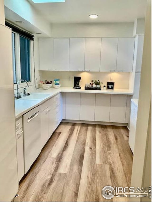 kitchen featuring white cabinets, light countertops, a sink, and appliances with stainless steel finishes