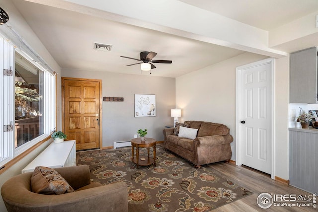 living area featuring visible vents, baseboard heating, ceiling fan, wood finished floors, and baseboards