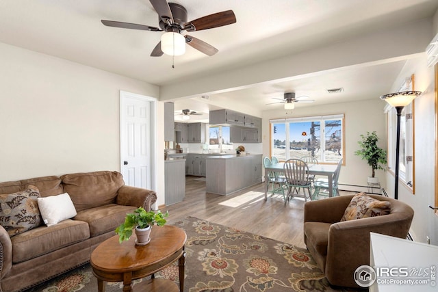 living room featuring ceiling fan, a baseboard radiator, light wood-type flooring, and visible vents