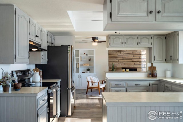 kitchen with light countertops, stainless steel electric range, a peninsula, and under cabinet range hood