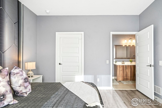 bedroom featuring connected bathroom and hardwood / wood-style flooring
