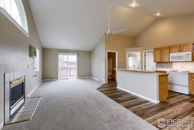 kitchen featuring white appliances, ceiling fan, high vaulted ceiling, a tiled fireplace, and dark carpet