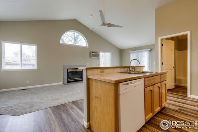 kitchen with sink, light brown cabinetry, dishwasher, a kitchen island with sink, and a tiled fireplace