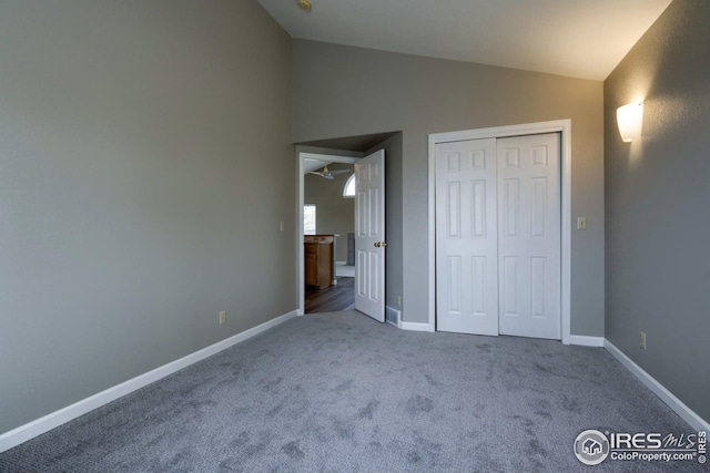 unfurnished bedroom featuring carpet flooring, vaulted ceiling, and a closet