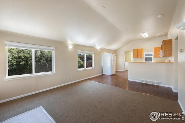 unfurnished living room featuring lofted ceiling and dark carpet