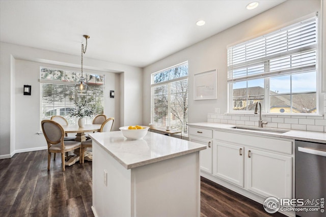 kitchen with dishwasher, a center island, dark wood finished floors, and a sink