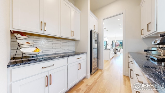 kitchen with dark stone counters, white cabinets, decorative backsplash, light wood-type flooring, and recessed lighting