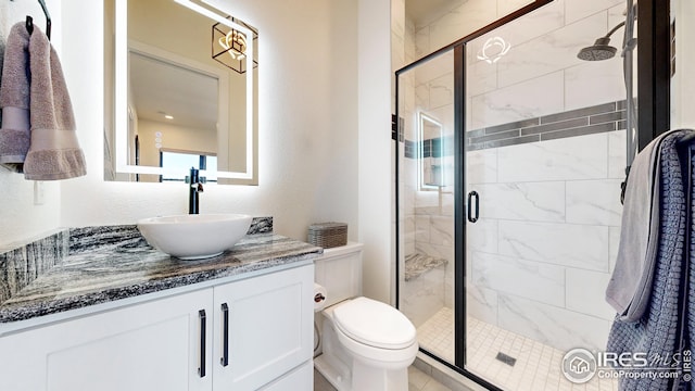 bathroom featuring toilet, a textured wall, vanity, and a shower stall