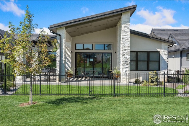 rear view of property featuring a fenced front yard, a lawn, and stucco siding