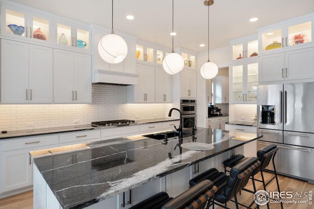 kitchen featuring appliances with stainless steel finishes, a sink, glass insert cabinets, and white cabinets