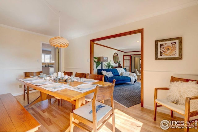 dining room with ornamental molding and light wood-type flooring