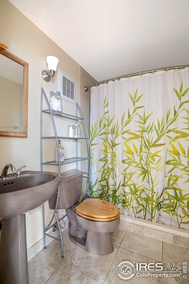 bathroom featuring walk in shower, toilet, and sink