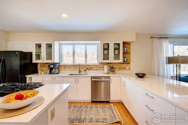 kitchen with sink, white cabinetry, black appliances, light hardwood / wood-style floors, and backsplash