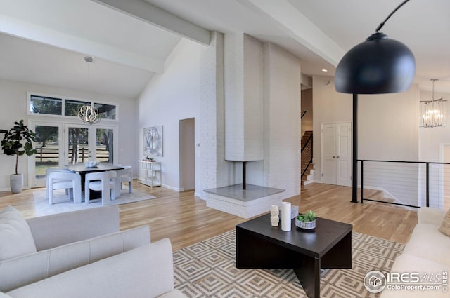 living room featuring beamed ceiling, a notable chandelier, high vaulted ceiling, and light hardwood / wood-style flooring