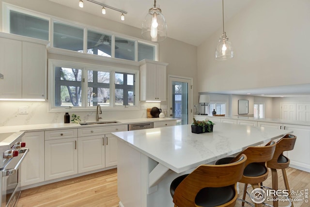 kitchen with sink, a breakfast bar, appliances with stainless steel finishes, a center island, and white cabinets