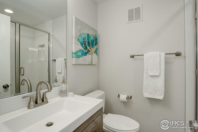 bathroom featuring vanity, an enclosed shower, and toilet