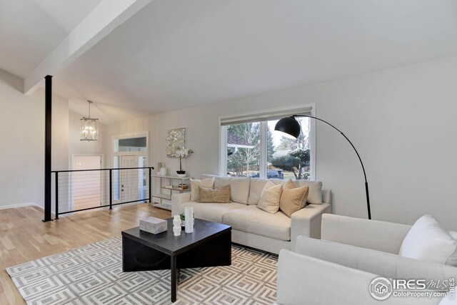 living room featuring vaulted ceiling with beams, an inviting chandelier, and light hardwood / wood-style flooring