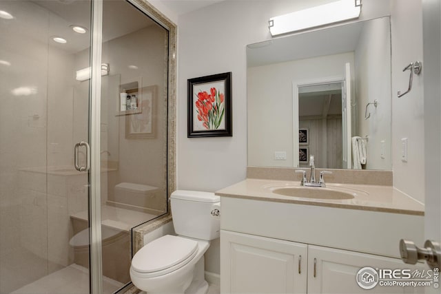 bathroom with vanity, a shower with shower door, and toilet