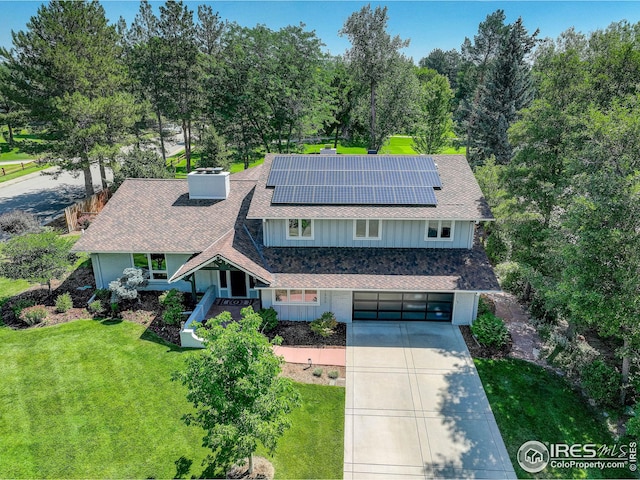 view of front facade with a garage, a front yard, and solar panels