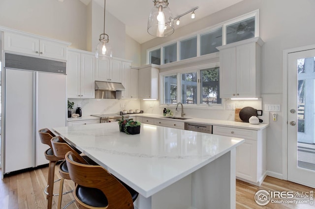 kitchen featuring sink, appliances with stainless steel finishes, white cabinetry, hanging light fixtures, and a kitchen island