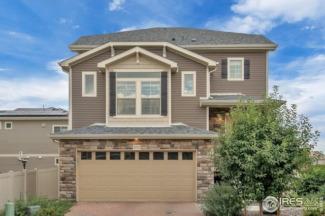 view of front of house featuring a shingled roof, fence, decorative driveway, a garage, and stone siding