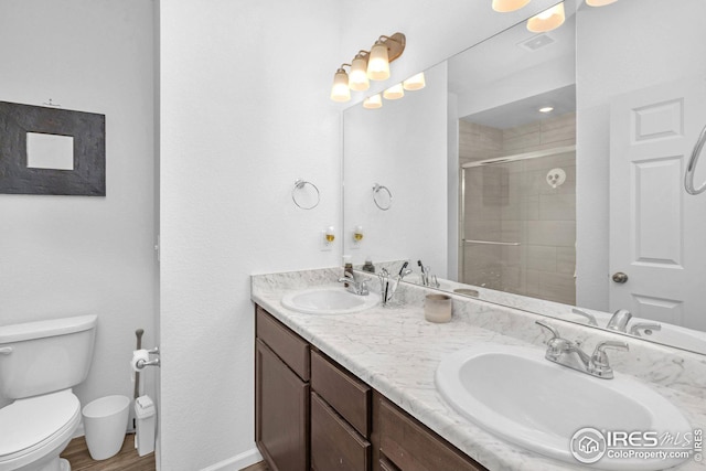 full bath featuring double vanity, a stall shower, toilet, and a sink