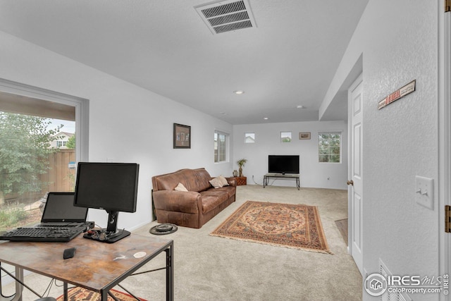 living area with visible vents and light colored carpet