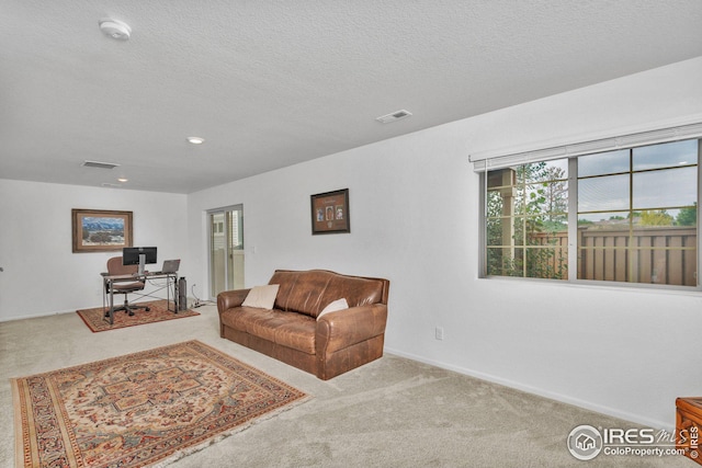 living area with baseboards, carpet, visible vents, and a textured ceiling