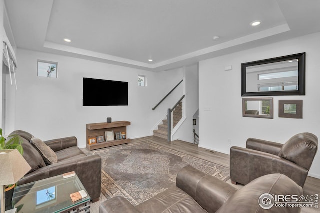 living room featuring stairway, recessed lighting, a tray ceiling, and wood finished floors