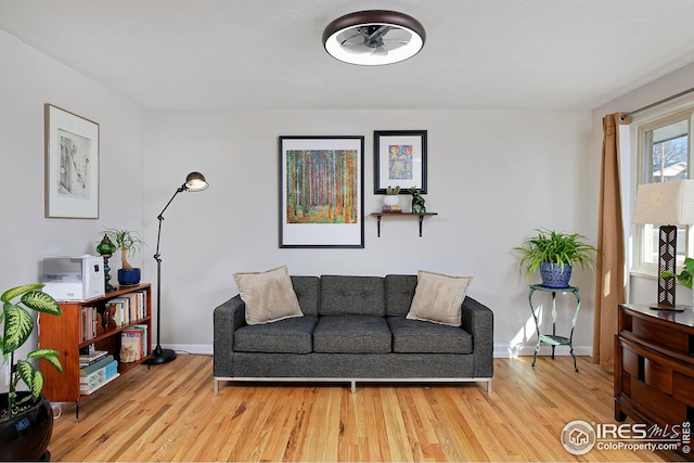 living area featuring baseboards and light wood finished floors