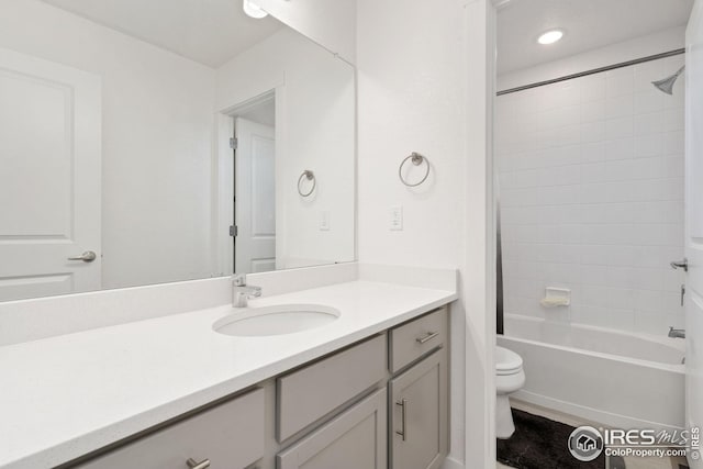 full bathroom with vanity, tiled shower / bath, and toilet