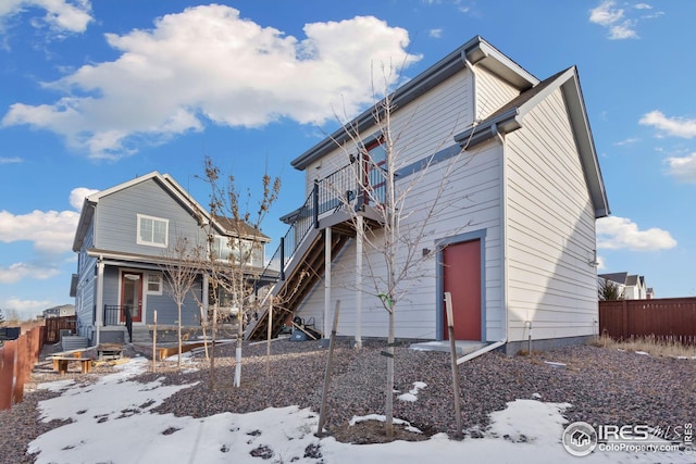 snow covered rear of property with a balcony