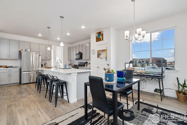 dining space with sink, a chandelier, and light hardwood / wood-style floors